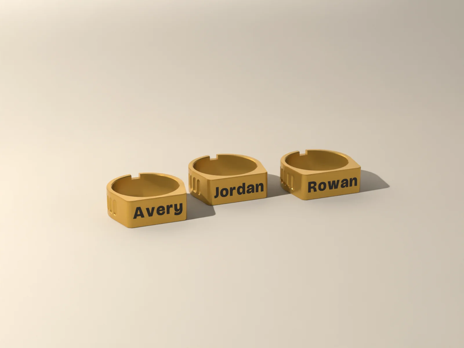 Three gold napkin rings with flat fronts carrying the names Avery, Jordan and Rowan inlaid in ink