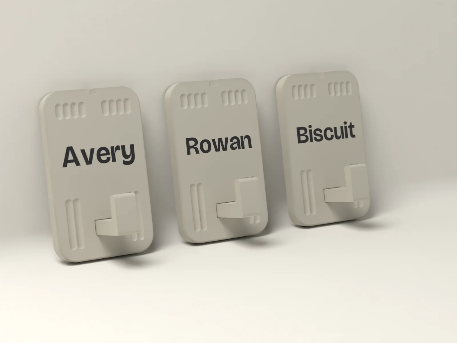 Three named wall hooks in Kiln, terracotta tiles with Avery, Rowan and Biscuit inlaid flush in Sand, each with a stout hook