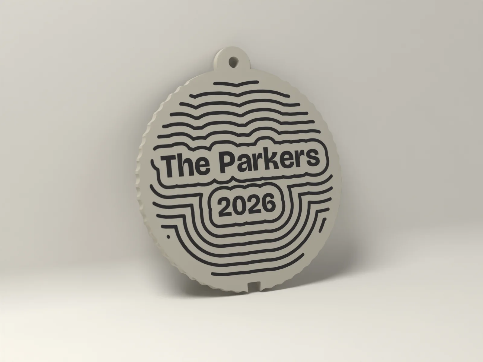 Flat personalized ornament in Bone, The Parkers and 2026 inlaid flush in Ink inside contour rings, with a fluted edge and a hanging loop