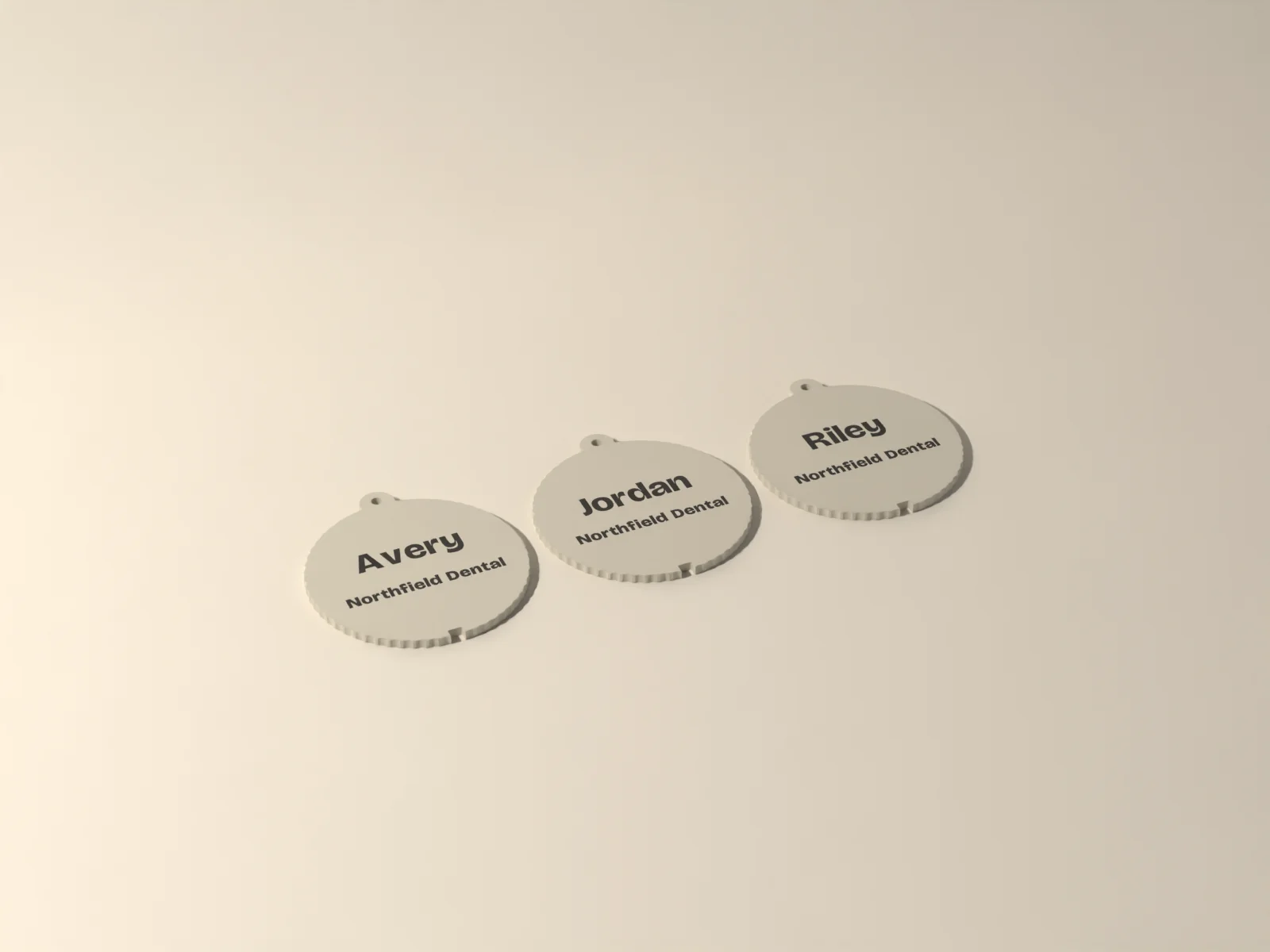 Ten bone ornaments with a name on each and Northfield Dental underneath, inlaid flush in ink