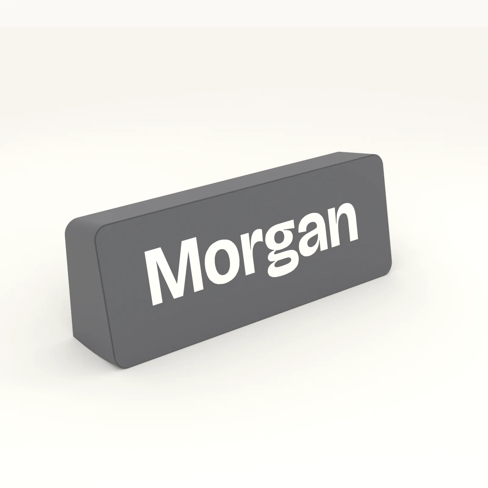 Desk name plaque in black with the name raised in white, standing on a desk