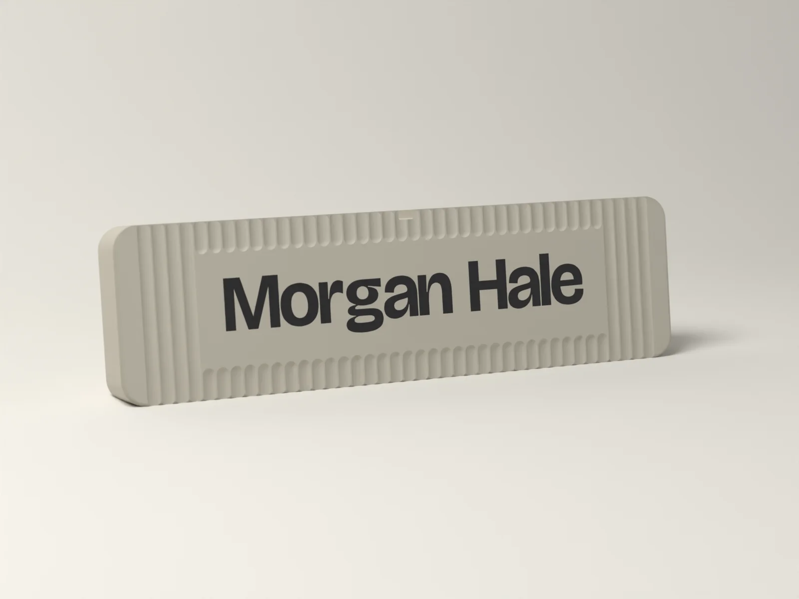 Desk name plate in the Fluted finish, Bone with Morgan Hale inlaid in Ink, finely fluted around a smooth name panel