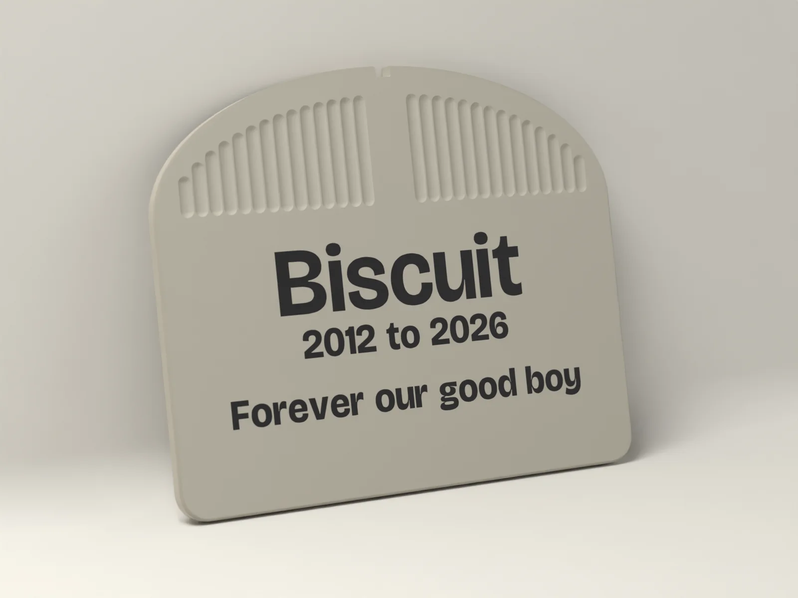 Pet memorial plaque in Bone with an arched top, the name Biscuit, the dates 2012 to 2026 and a short line inlaid in Ink