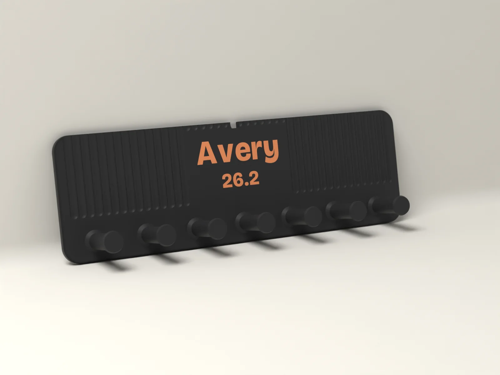 Fluted medal hanger in Ink with Avery and 26.2 inlaid in Ember above a row of seven round pegs