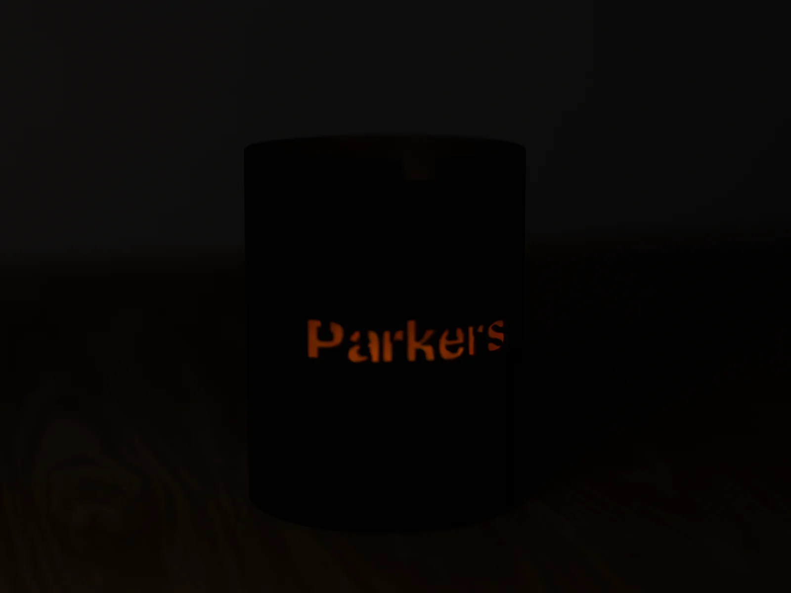 Luminary lantern lit in a dark room, the letters glowing in the sleeve color