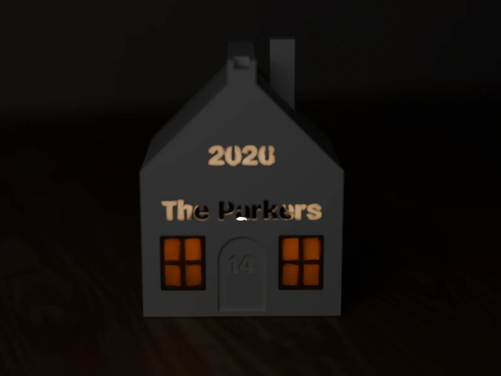 Village house lit from inside in a dark room, the windows, the name and the year glowing