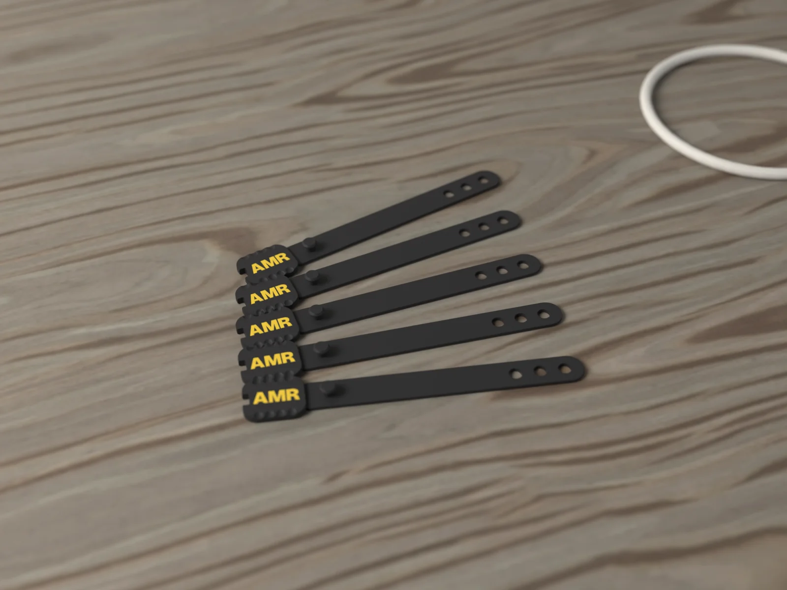 Five cord keepers fanned on a walnut desk beside a coiled white charging cable